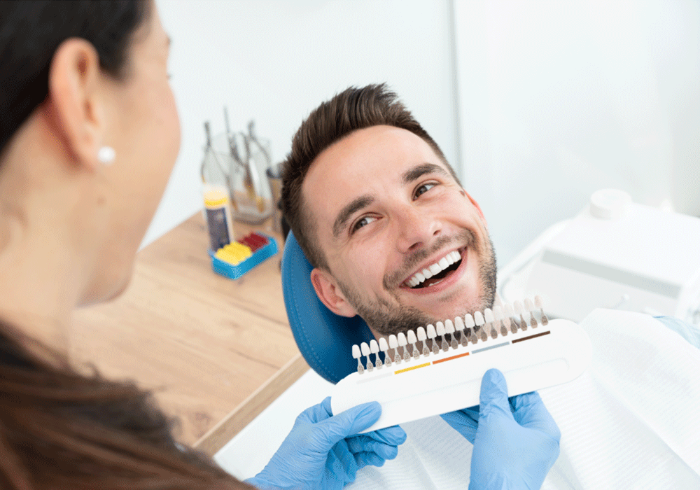 smiling patient with doctor holding tooth shade guide