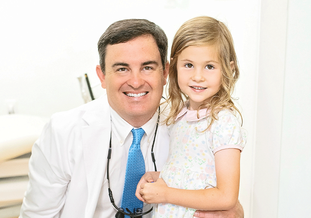 Dr. Green wearing a white coat and blue tie, with a stethoscope around the neck, indicating a professional role, likely in the medical or dental field. The second person is a child in a light-colored floral dress.